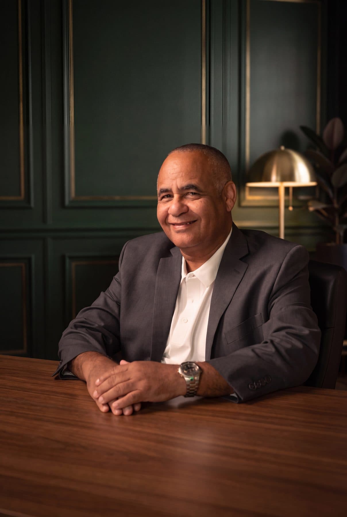 Ruben Rodriguez of RSCCA seated at a walnut table, hands folded, smiling at the camera.